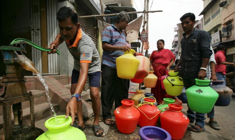 A man uses a hand-pump to fill up a container with drinking water as others wait in a queue on a street in Chennai. Chennai Water Crisis