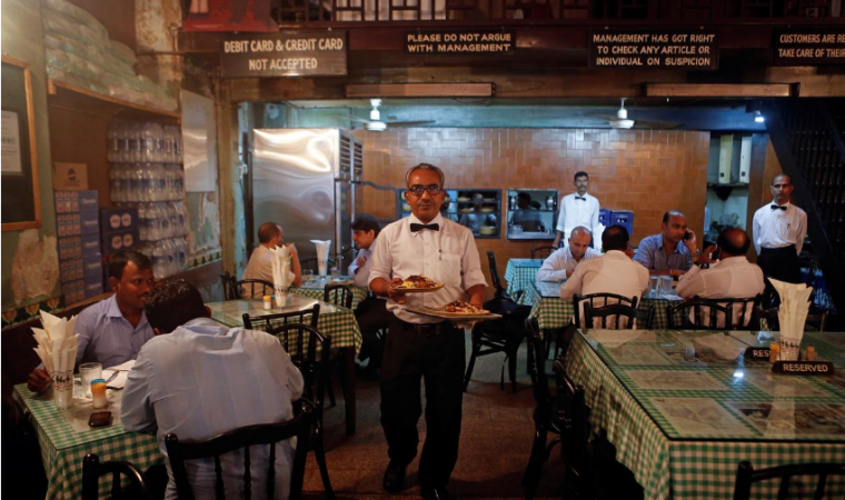 A waiter carries plates of food for customers at a restaurant in Mumbai, September 19, 2013. indian economy slowdown
