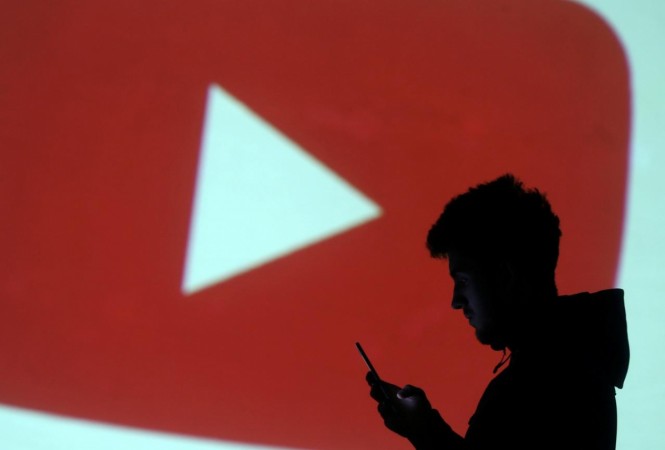 Silhouette of mobile user is seen next to a screen projection of Youtube logo in this picture illustration taken March 28, 2018. youtube child privacy violations