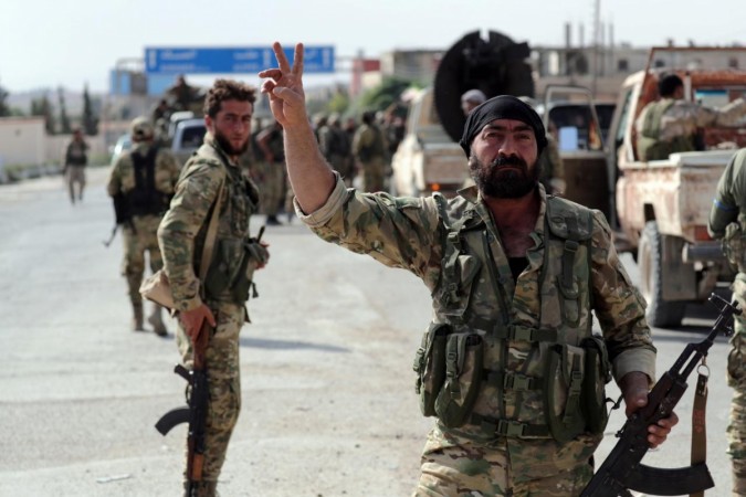 A Turkey-backed Syrian rebel fighter gestures to the camera at the border town of Tel Abyad, Syria, October 14, 2019. Turkey attacking Kurdistan
