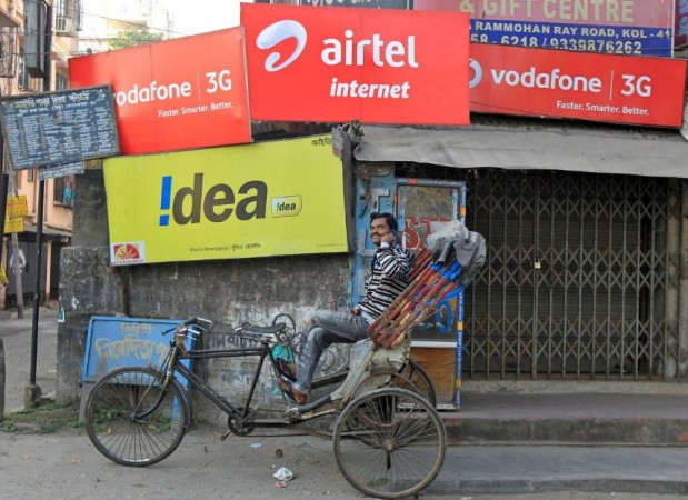 A rickshaw puller speaks on his mobile phone in front of advertisement billboards belonging to telecom companies in Kolkata, India, February 3, 2014. Telecom India