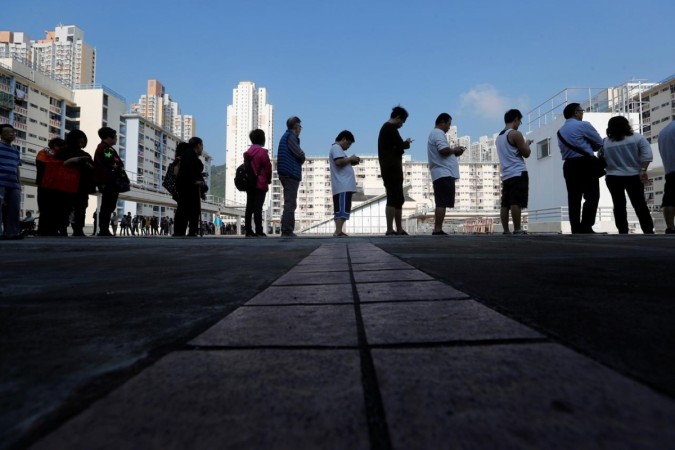 Voters queue to vote at a polling station during district council local elections in Hong Kong, China. Hong Kong