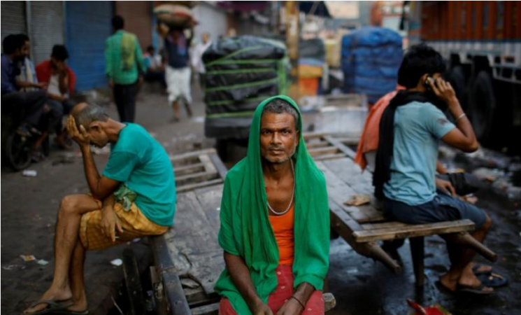 Migrant labourers sit on a handcart as they wait for work at a wholesale market in the old quarters of Delhi, India, October 10, 2019. Indian economy