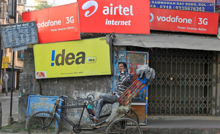 A rickshaw puller speaks on his mobile phone as he waits for customers in front of advertisement billboards belonging to telecom companies in Kolkata February 3, 2014. telecom sector