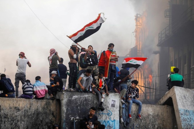 An Iraqi demonstrator carries the Iraqi flag during ongoing anti-government protests, in Baghdad, Iraq. Iraq protests