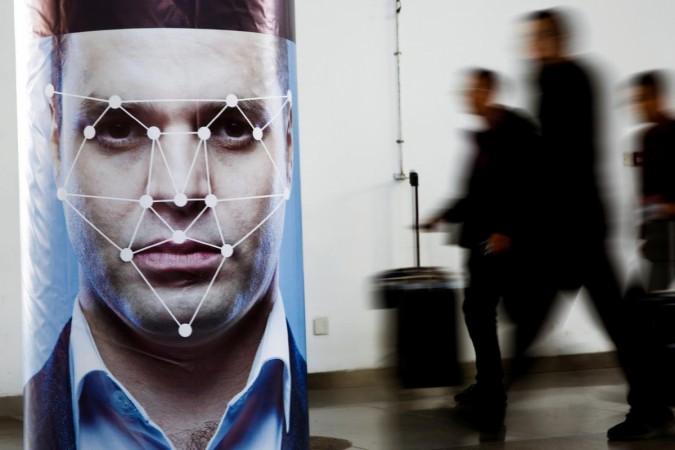 People walk past a poster simulating facial recognition software at the Security China 2018 exhibition. Facial recognition