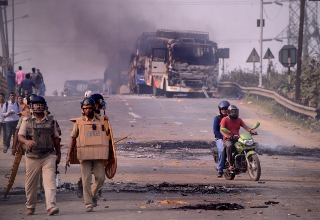 Howrah: Police personnel patrol a street after violence broke out as angry protesters burnt vehicles during a demonstration against the Citizenship Amendment Act (CAA) 2019, in West Bengal's Howrah on Dec 14, 2019. Violent protests against the new citizenship law spread to more areas in West Bengal on Saturday as mobs torched buses, set afire railway property and blockaded road and rail disrupting train and vehicular movement.