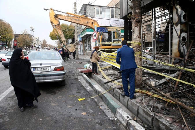 People walk near a burnt bank in Tehran. Iran protests