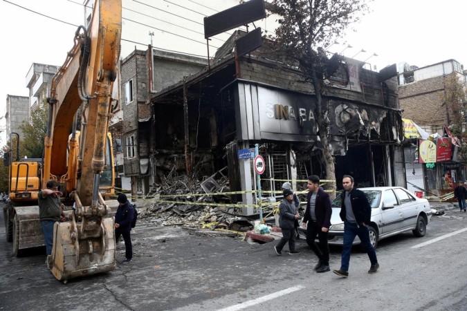 People walk near a burnt bank in Tehran. Iran protests