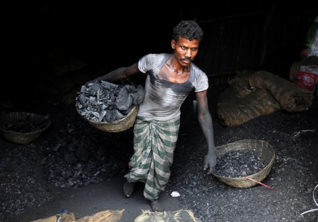 A worker carries coal in a basket in a industrial area in Mumbai. Coal