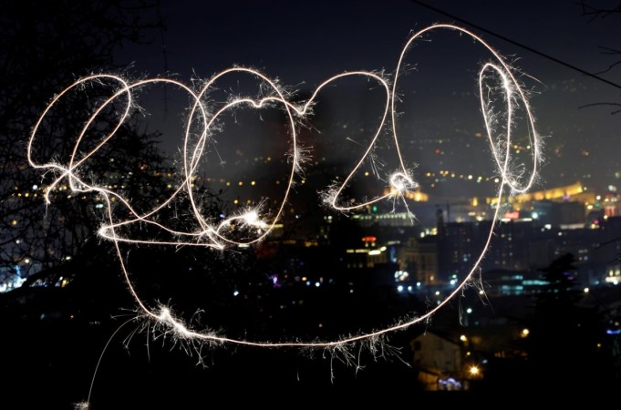 A girl with sparkle writes 2020 during New Year celebration. 2020