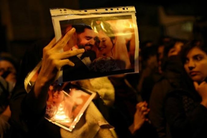A woman holds a picture of newlyweds, victims of the crash of the Boeing 737-800 plane, flight PS 752, as people gather to show their sympathy in Tehran. Iran protests