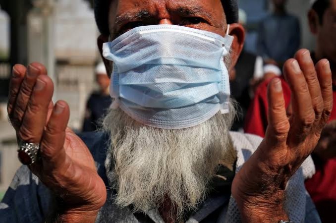 A man wearing a mask prays for the victims of coronavirus. Coronavirus masks