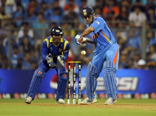 India's captain Mahendra Singh Dhoni plays a shot as Sri Lanka's captain and wicketkeeper Kumar Sangakkara (L) looks on during their ICC Cricket World Cup final match in Mumbai April 2, 2011.