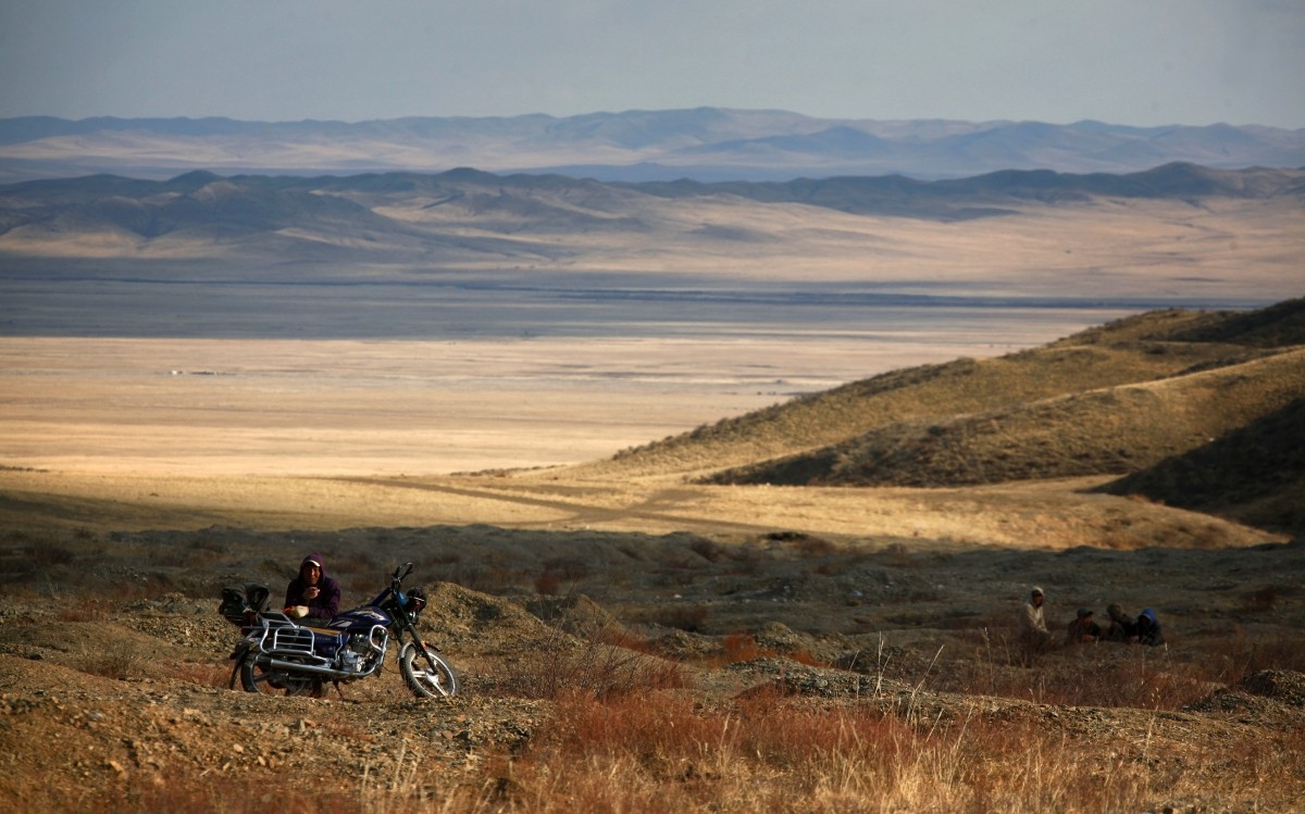 A small-scale miner takes a break from digging on hills surrounding grasslands located around 200km (62 miles) south-west of the Mongolian capital city Ulan Bator April 4, 2012. Mongolia