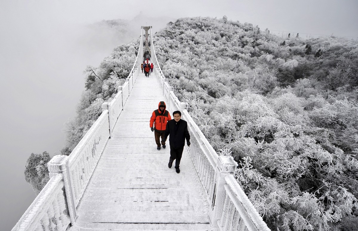 Tourists walk on a bridge covered by frosty fog on the Tianmen Mountain resort in Zhangjiajie, Hunan province, January 29, 2015. China