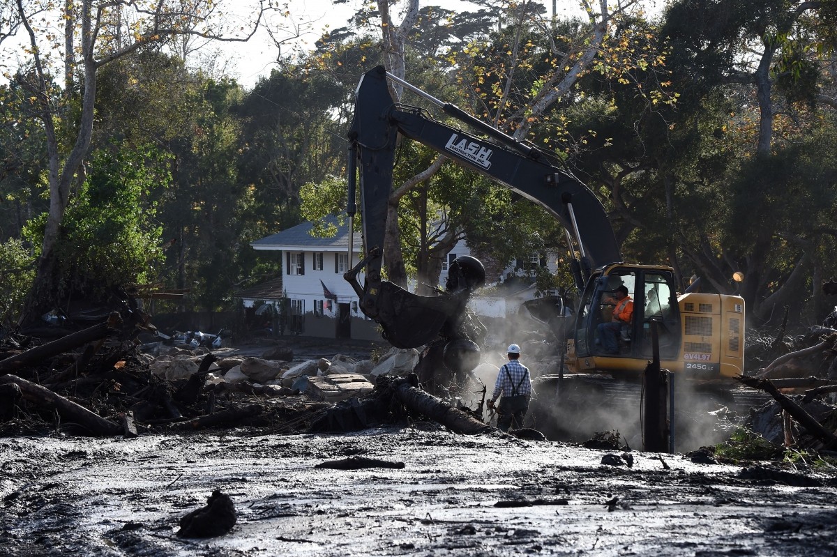 Workers use heavy machinery to clear mud and debris from an area where homes were destroyed by mudslides, in Montecito, California California mudslides
