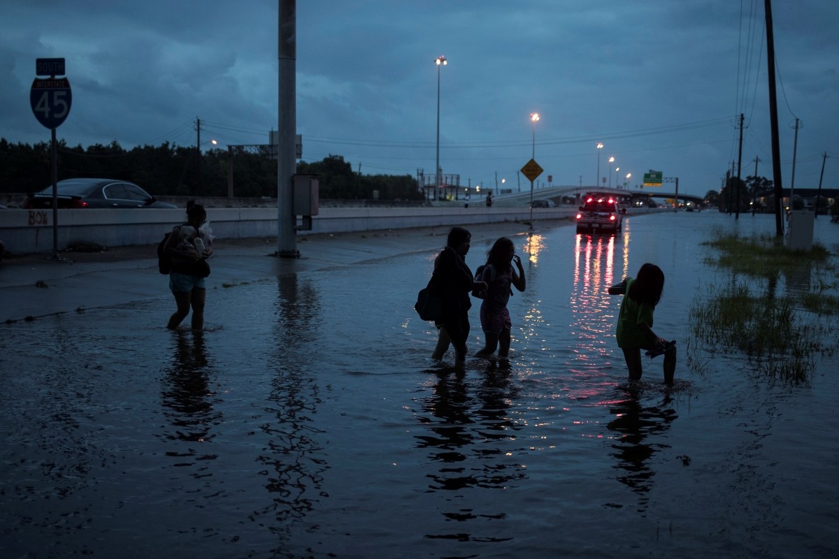 People walk through flood waters from Tropical Storm Harvey on the feeder road of Interstate 45 in Houston, Texas, U.S Tropical Storm Harvey