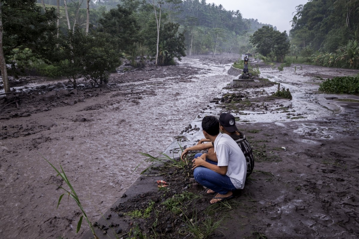 Volcanic material from Mount Agung flows through a local river in Gesing Village while villagers are seen watching nearby Bali volcano