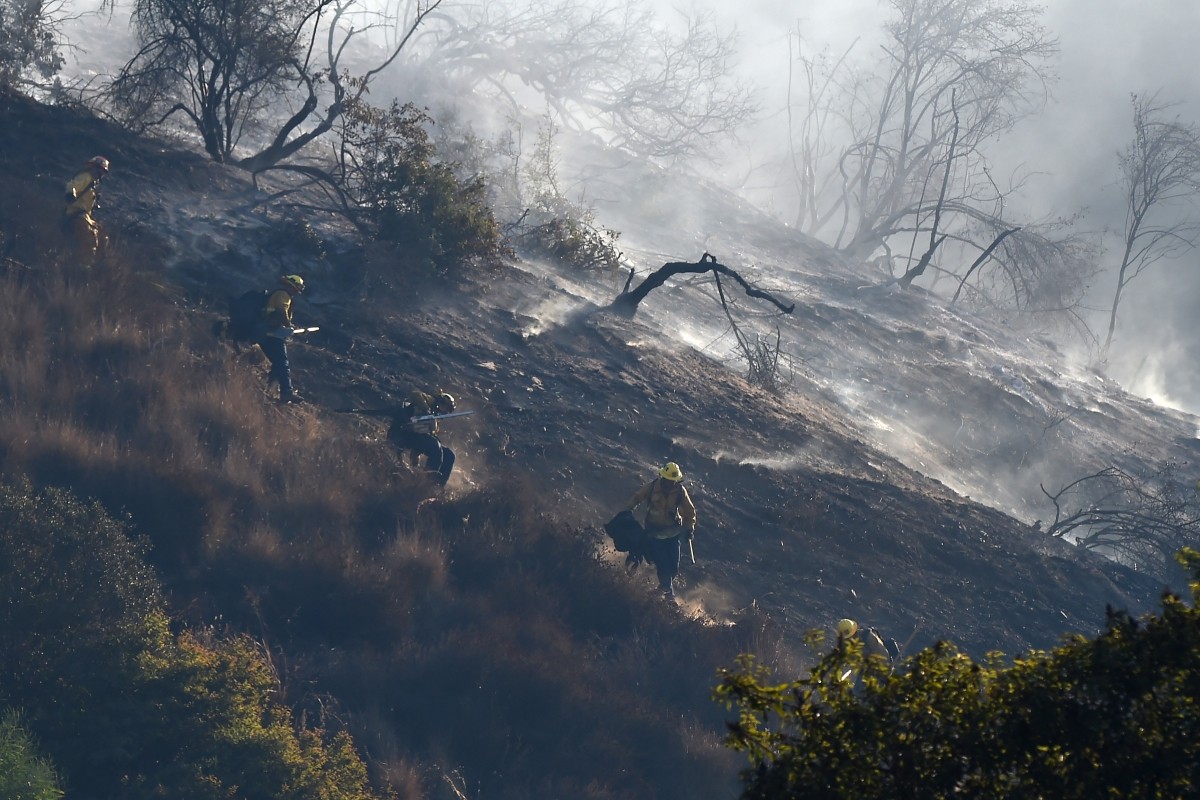 A fire team hand crew descends a steep slope to prevent fire from jumping to the west side of the 405 freeway, at the Skirball Fire along the 405 freeway near the Bel Air area Skirball Fire