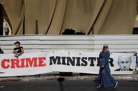 A woman walks past a banner depicting Israeli Prime Minister Benjamin Netanyahu and the words Netanyahu