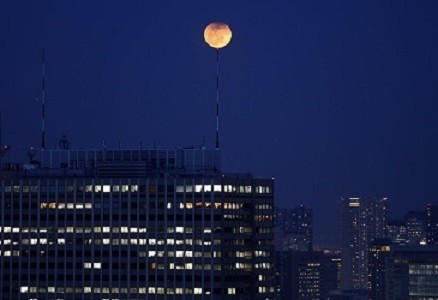 The partial lunar eclipse is seen atop an antenna installed on the roof of a high-rise building in Tokyo (Reuters)