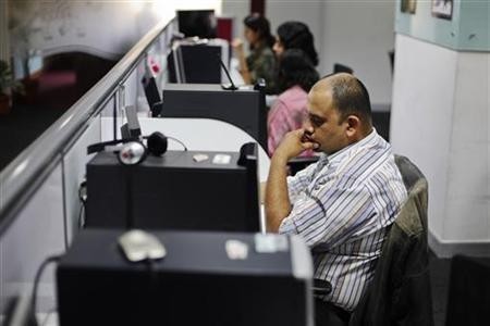 Office workers sit in front of their workstations on the floor of an outsourcing centre in Bangalore, February 29, 2012.