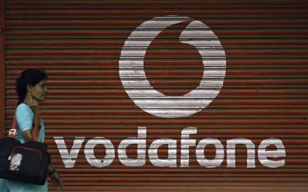 A woman walks past a large logo of Vodafone displayed on a shop in Mumbai May 20, 2010.