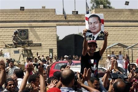 A supporter holds a poster of Hosni Mubarak outside Tora prison