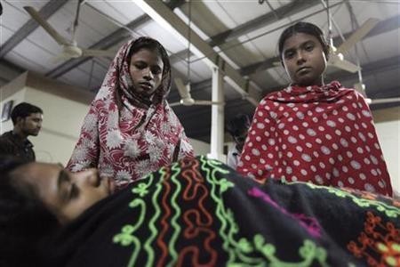 Colleagues stand beside Asma, a garment worker, who was injured in a devastating fire at a garment factory in Savar, outskirts of Dhaka November 24, 2012. REUTERS/Andrew Biraj Fire in Bangladesh clothing factory