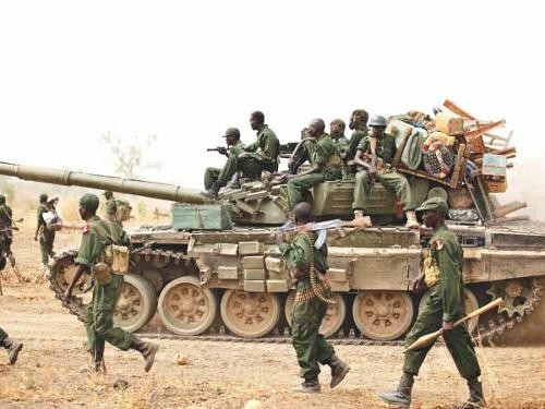 South Sudanese soldiers walk alongside a tank as they withdraw from the town of Jau, at the disputed border with Sudan .