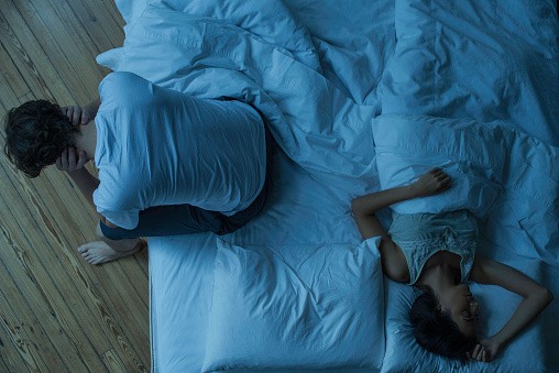 Man unable to sleep while wife sleeps comfortably unaware. Insomnia