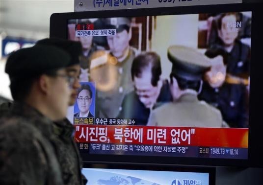 South Korean soldiers walk past a television showing reports on the execution of Jang Song Thaek, who is North Korean leader Kim Jong Un's uncle, at a railway station in Seoul December 13, 2013.