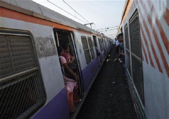 Passengers ride at the open doorways of commuter trains in Mumbai