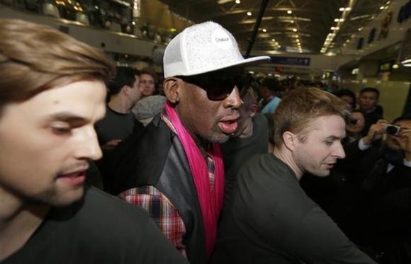 Former NBA basketball player Dennis Rodman (C) is protected by staff members as he arrives at the Beijing Capital International Airport to leave for Pyongyang, in Beijing, January 6, 2014.