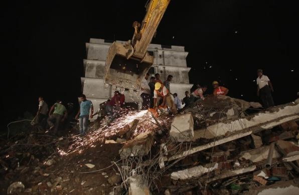 Rescue workers use a cutting tool to search for survivors after a residential building collapsed in Thane, on the outskirts of Mumbai April 4, 2013.