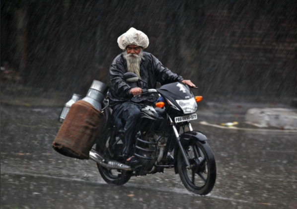 FILE PHOTO: A milkman rides a motorcycle during a heavy rain shower in the northern Indian city of Chandigarh July 2, 2014. REUTERS/Ajay Verma FILE PHOTO: A milkman rides a motorcycle during a heavy rain shower in the northern Indian city of Chandigarh July 2, 2014. REUTERS/Ajay Verma