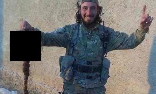 An ISIS militant posing with the head of a captured Kurdish female fighter