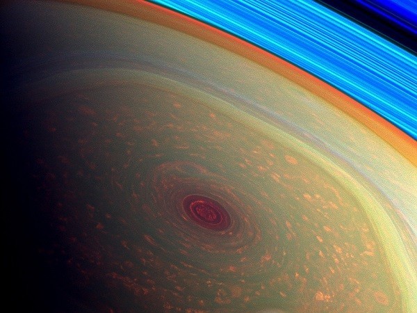 This spectacular, vertigo inducing, false-color image from NASA's Cassini mission highlights the storms at Saturn's north pole. The angry eye of a hurricane-like storm appears dark red while the fast-moving hexagonal jet stream framing it is a yellowish green. Low-lying clouds circling inside the hexagonal feature appear as muted orange color. A second, smaller vortex pops out in teal at the lower right of the image. The rings of Saturn appear in vivid blue at the top right. (Credit: NASA/JPL-Caltech/SSI) This spectacular, vertigo inducing, false-color image from NASA's Cassini mission highlights the storms at Saturn's north pole.