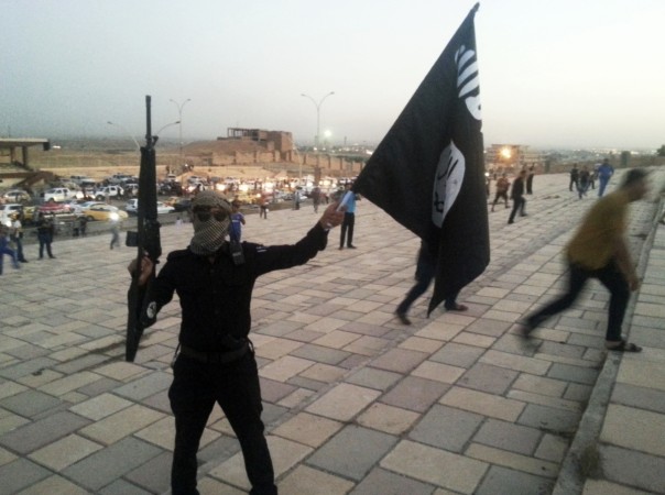 A militant holds an Isis flag on a street in the city of Mosul on 23, June, 2014. isis militant waves flag