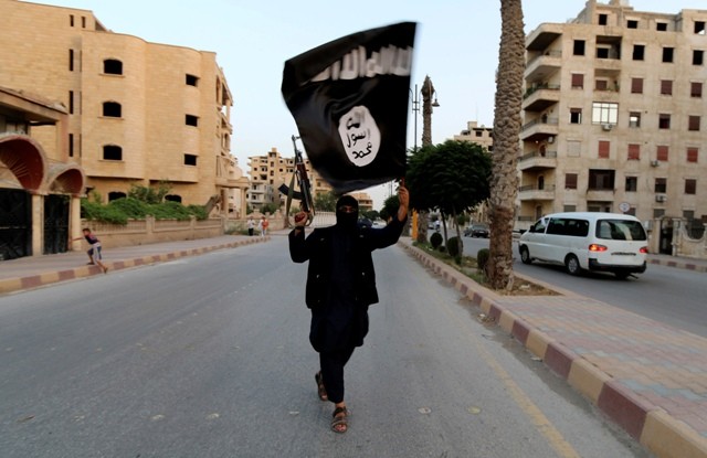 A member loyal to the Islamic State in Iraq and the Levant (ISIL) waves an ISIL flag in Raqqa on 29 June 2014. Islamic State in Iraq and the Levant (ISIL)