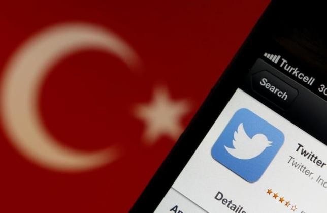 A Twitter logo on an iPhone display is pictured next to a Turkish flag in this photo illustration taken in Istanbul March 21, 2014