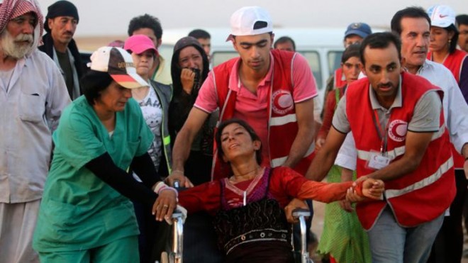 Members of the Kurdish Red Crescent helping a Yazidi woman