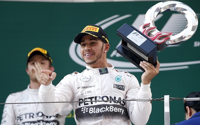 Mercedes driver Lewis Hamilton of Britain (R) gestures with his trophy as he celebrates his victory in front of his team mate second placed Nico Rosberg of Germany on the podium after the Chinese Grand Prix at the Shanghai International Circuit Chinese Grand Prix
