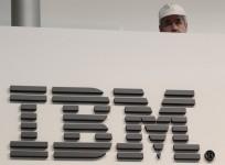 A worker is pictured behind a logo at the IBM stand on the CeBIT computer fair in Hanover