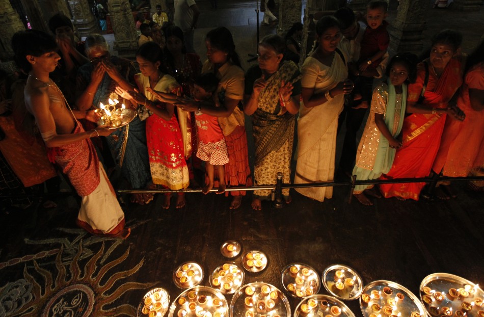 Hindu devotees pray in front of oil lamps during Pongal harvest festival. Pongal celebration