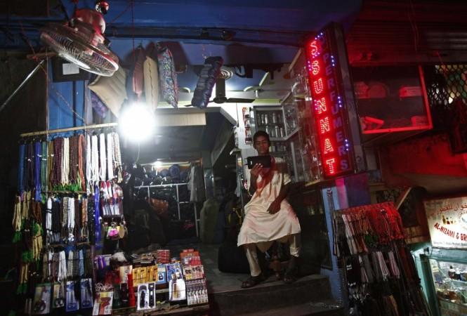 A shopkeeper watches a screen as he waits for customers at his illuminated shop after the electricity was restored in New Delhi (Reuters) Blackouts in India