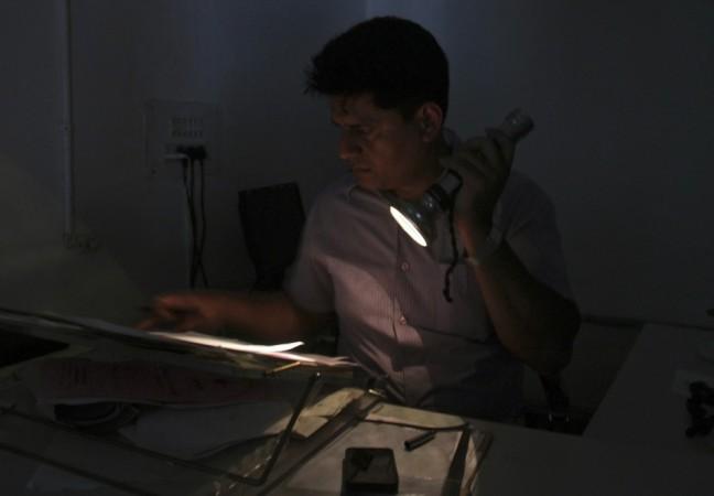 An officer reads documents with the help of a torch at the driving registration and license authority office during a power-cut in Chandigarh (Reuters) Blackouts in India