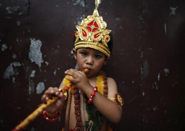 A boy dressed as Lord Krishna, a Hindu deity, blows on a flute as he participates in a parade to mark the Gaijatra Festival in Kathmandu (Reuters) Janmashtami