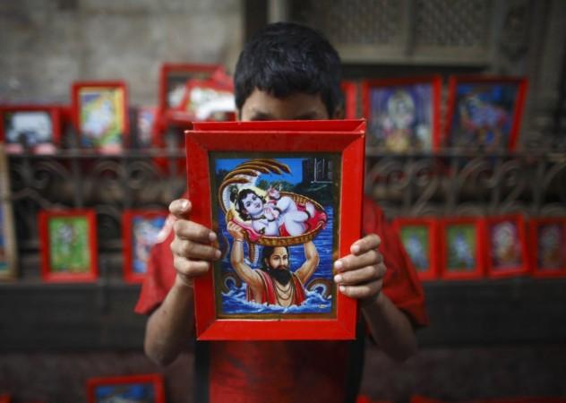 A boy holds up a portrait of Hindu god Krishna that he is selling, to passing devotees near the Krishna Temple in Lalitpur (Reuters) Janmashtami